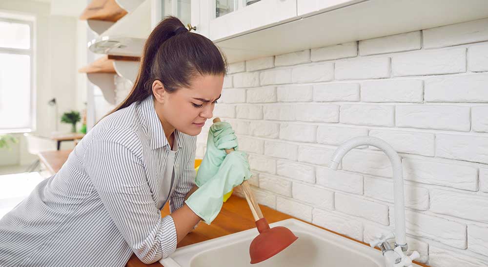 frustrated homeowner standing over a clogged drain